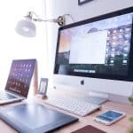 silver iMac near iPhone on brown wooden table