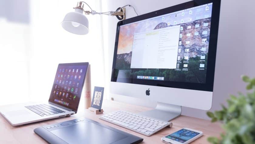 silver iMac near iPhone on brown wooden table